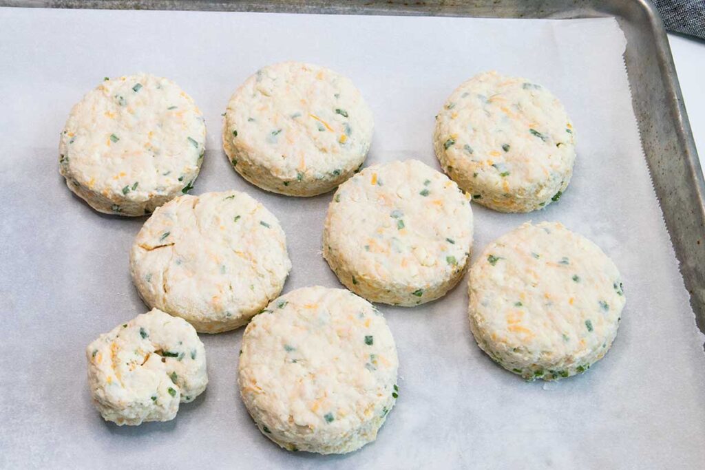 Cut cheddar chive biscuits on a parchment lined baking sheet.