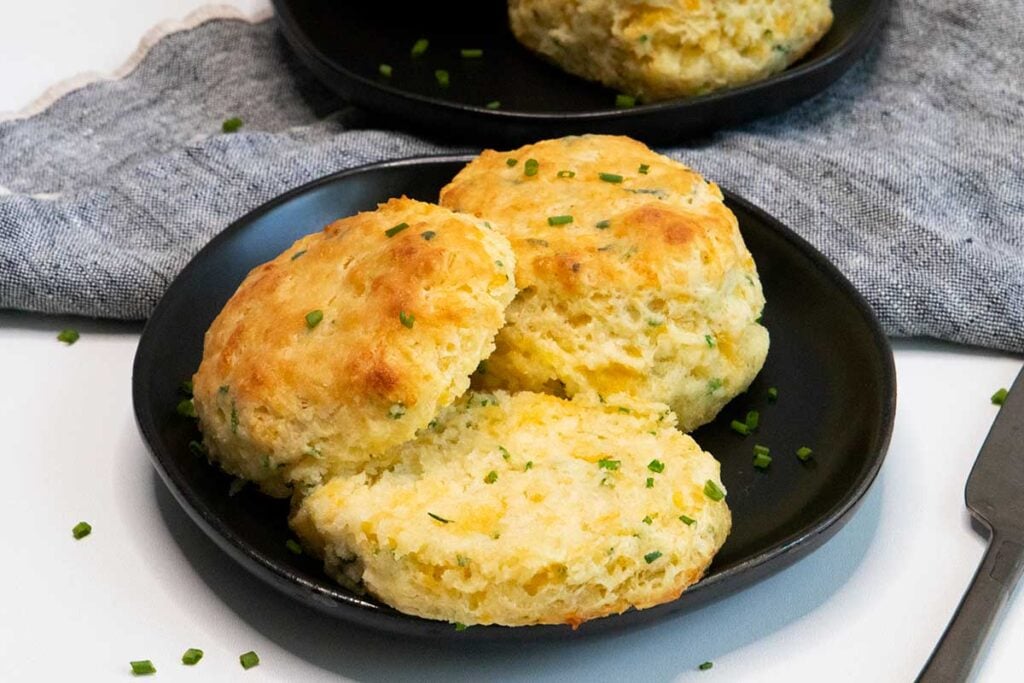 Cheddar chive biscuits on black plate.