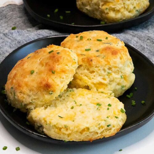 Cheddar chive biscuits on black plate.