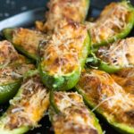 Jalapeno poppers on a black plate.