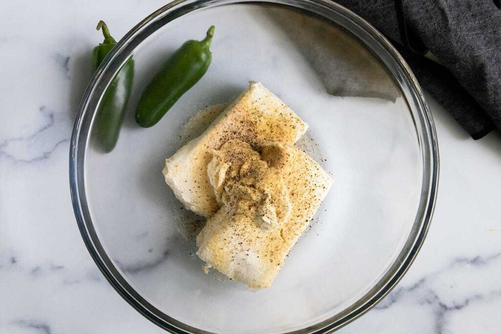 Jalapeno popper cheese ball ingredients in a glass bowl.