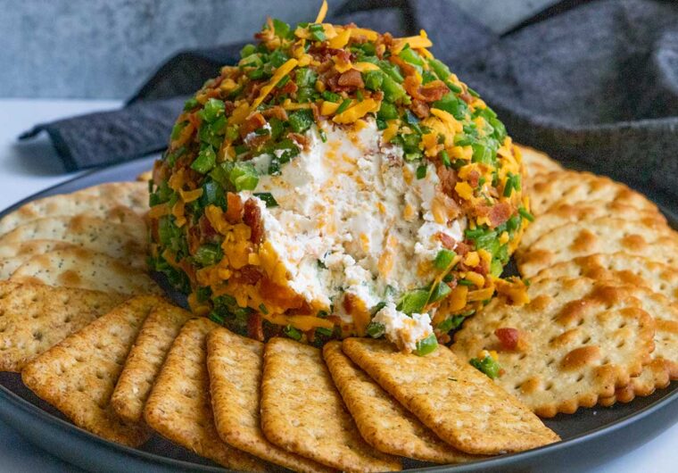 Jalapeno Popper Cheese Ball on a black plate with crackers