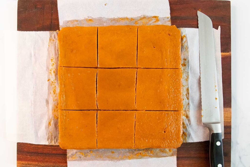 Pumpkin pie bars sliced into servings on a cutting board.