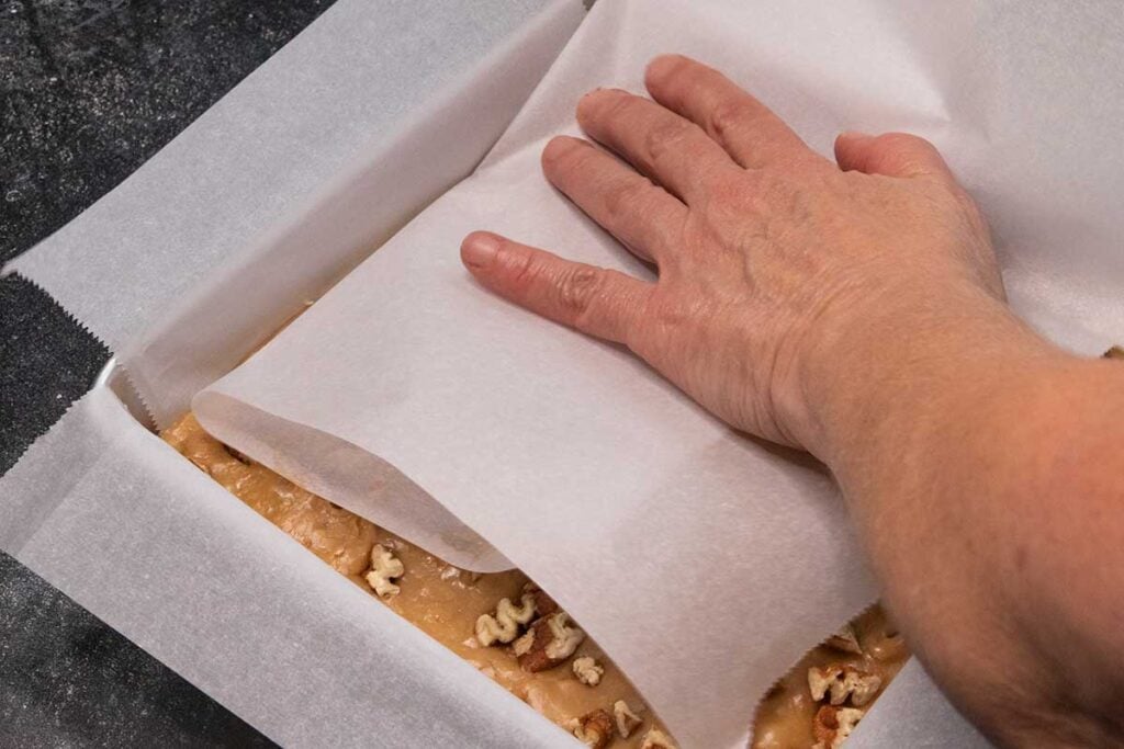 pressing pecan pieces in with parchment paper