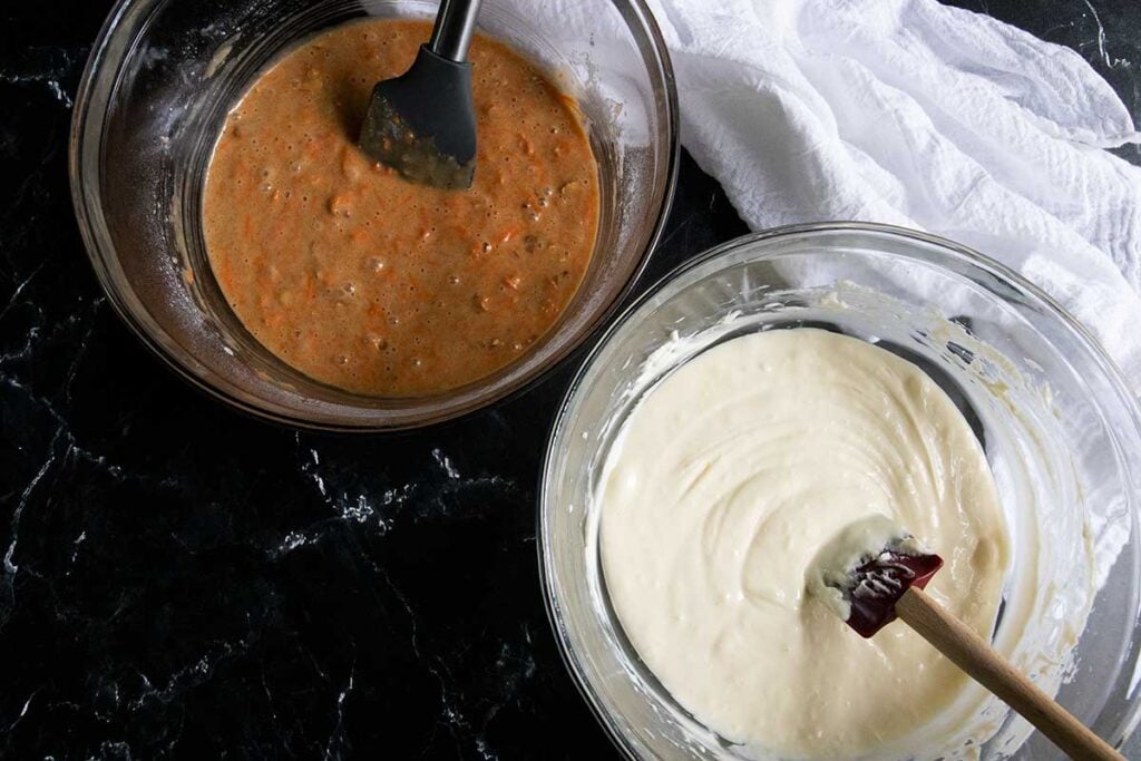 Cheesecake batter and carrot cake batter in glass mixing bowls.