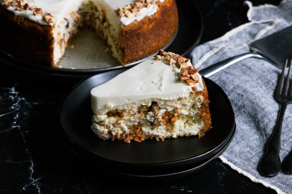 slice of carrot cake cheesecake on black plate