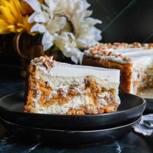 A slice of carrot cake cheesecake on black plate.