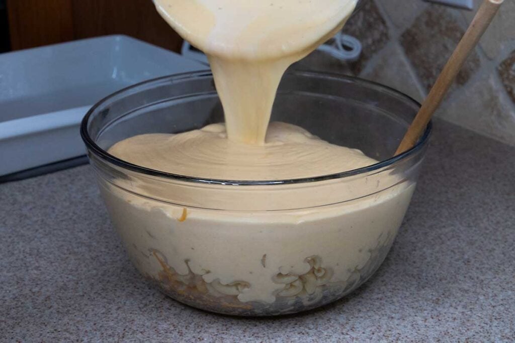 Adding cheese sauce to macaroni.