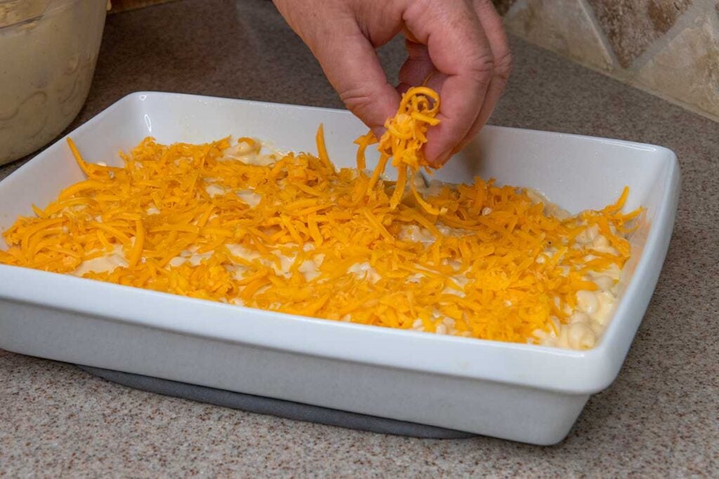 adding a layer of cheese to pasta mixture for macaroni and cheese