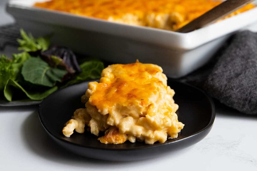 A serving of macaroni and cheese on a black plate.