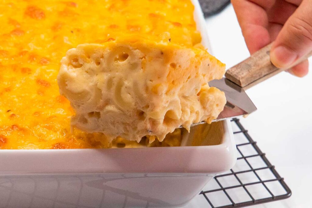 Getting a portion of baked macaroni and cheese out of the baking dish.