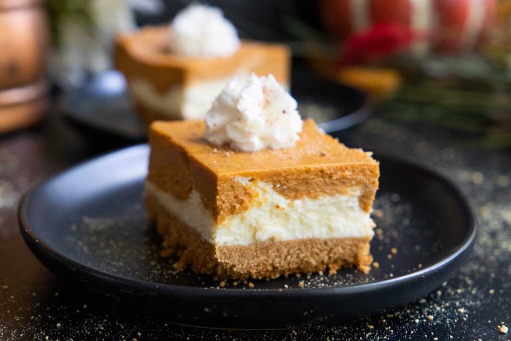 Pumpkin cheesecake bar on a black plate.