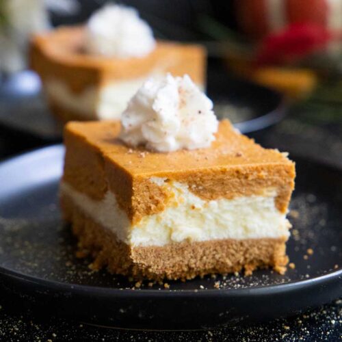 Pumpkin cheesecake bar on a black plate.