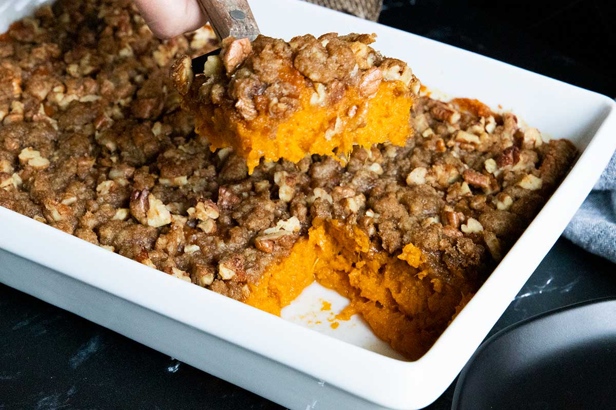 A serving of sweet potato casserole lifted over the pan.