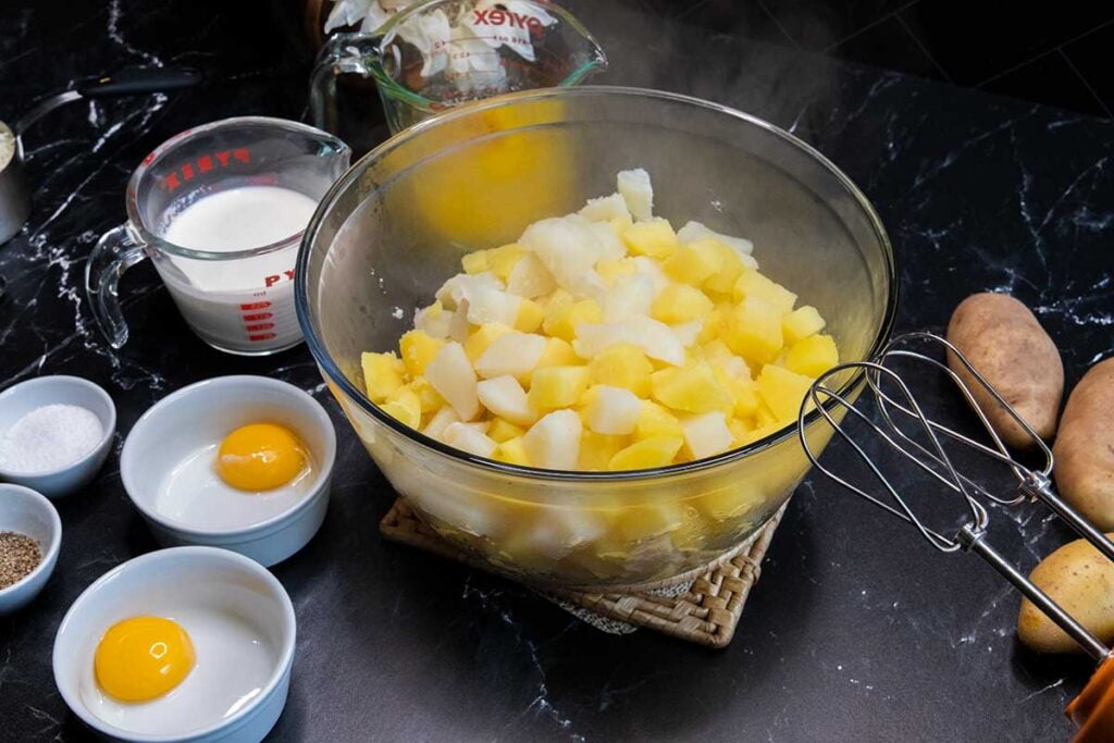 Boiled potatoes with remaining ingredients around.
