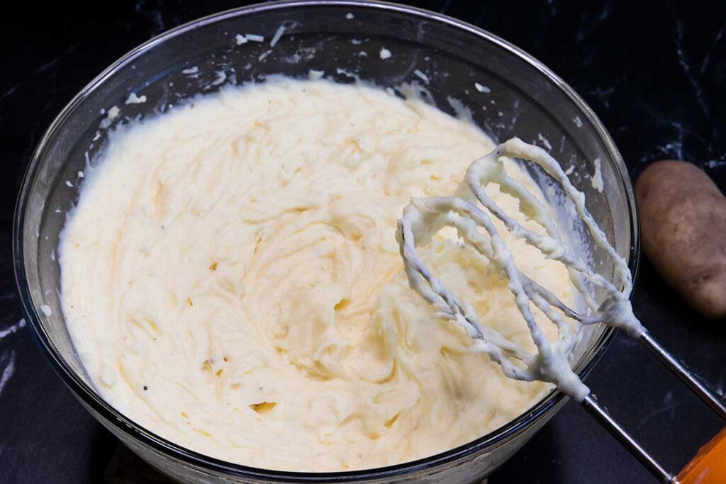 Whipped potatoes in a glass mixing bowl.