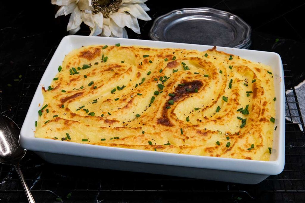 Whipped potatoes in a white casserole dish garnished with chopped chives.