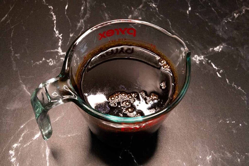 Boiled stout and molasses in a glass measuring cup.