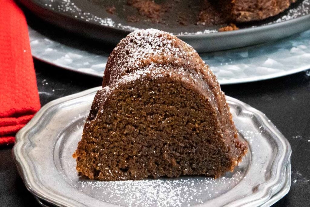 A slice of Gramercy Tavern gingerbread on silver plate garnished with powdered sugar.