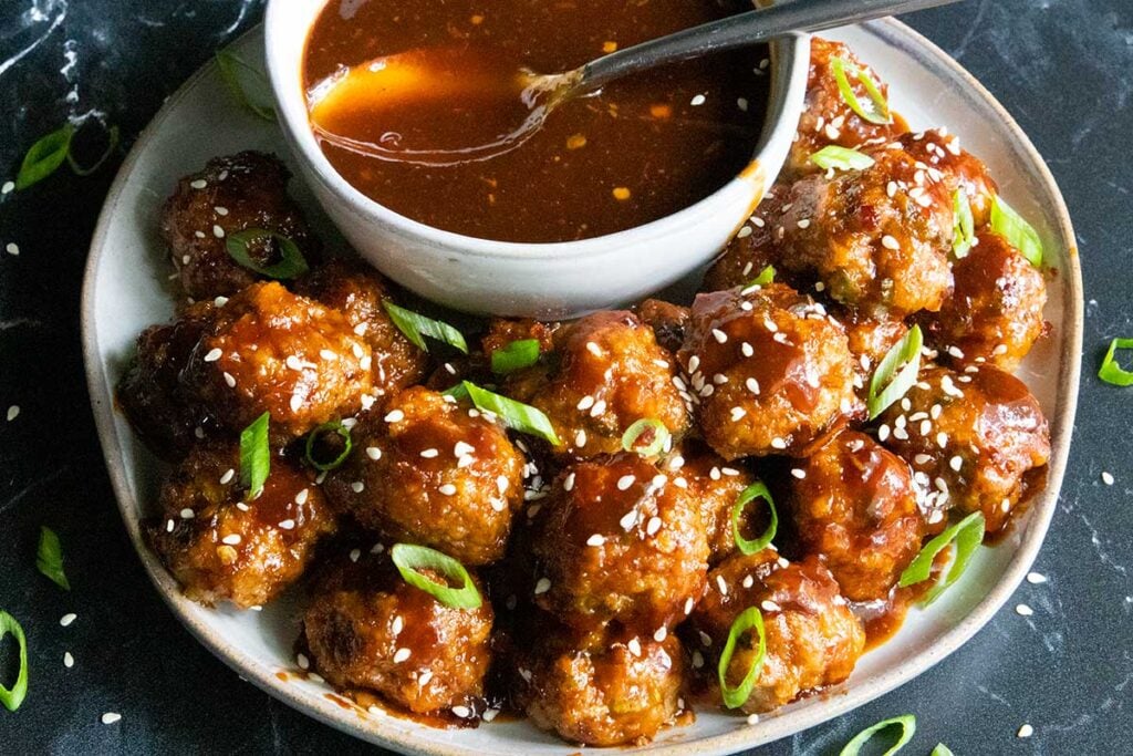 sweet and spicy meatballs on a plate with dipping sauce