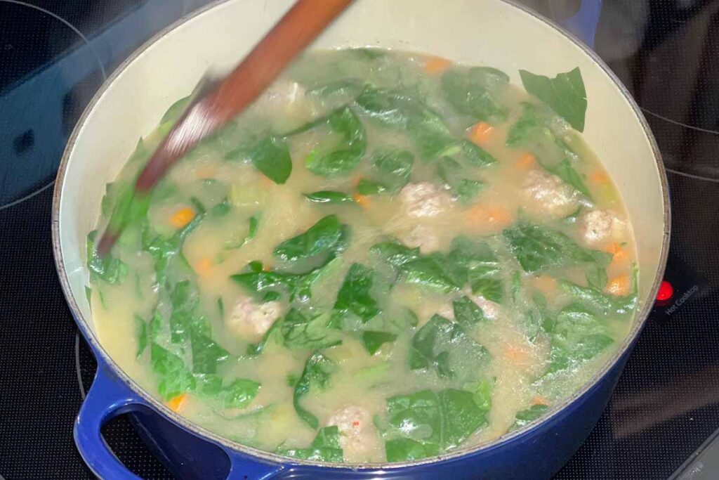 Spinach being stirred to the pot.