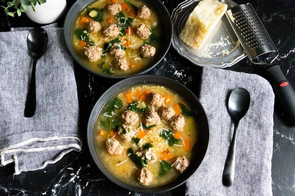 Italian wedding soup in black bowls.