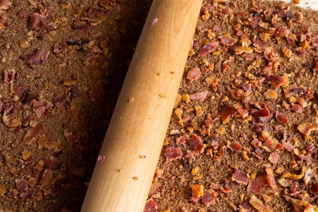 Pressing the bacon into the dough.