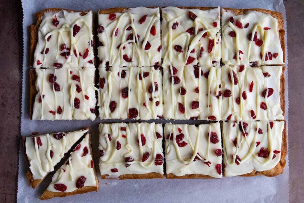 Sliced cranberry bliss bars on parchment paper.