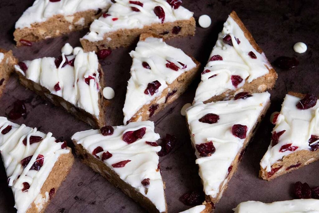 Slices of cranberry bliss bars on a sheet pan.