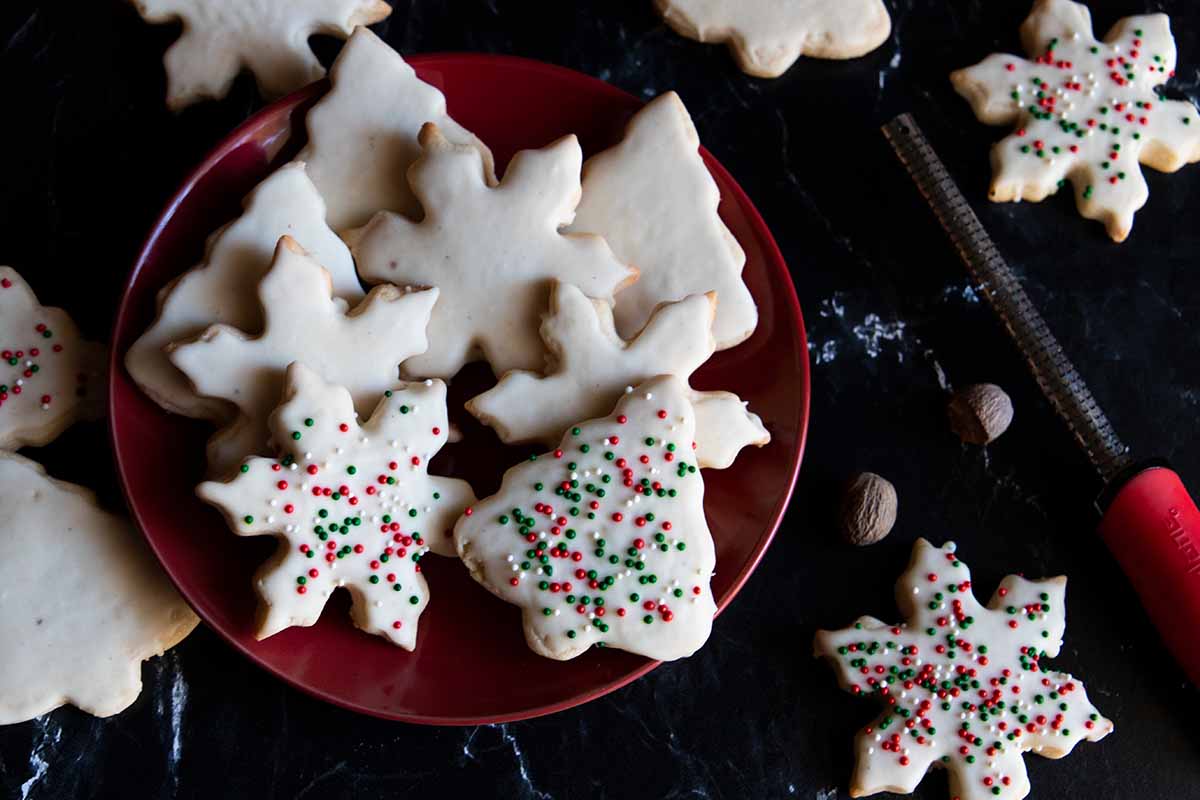 Eggnog cookies stacked on a plate on a dark surface.