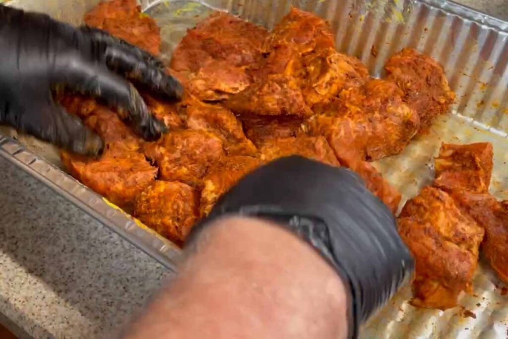 applying rub to pork butt cubes