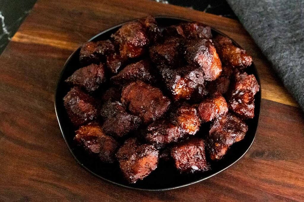 Pork butt burnt ends on a black plate