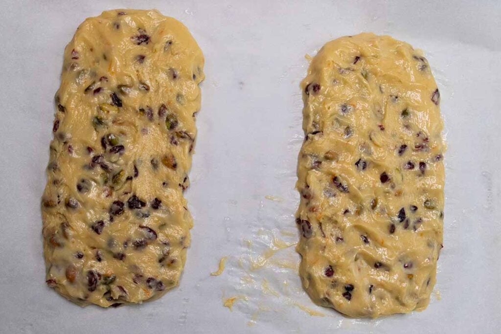 Cranberry pistachio biscotti dough formed into logs on parchment paper.