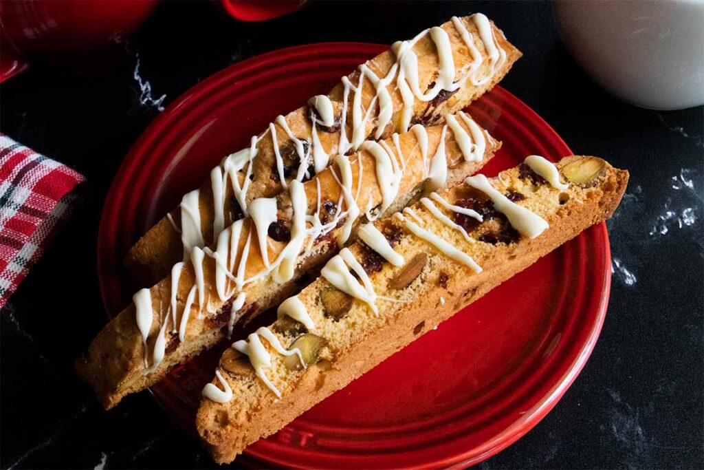 Slices of cranberry pistachio biscotti on a dark plate.