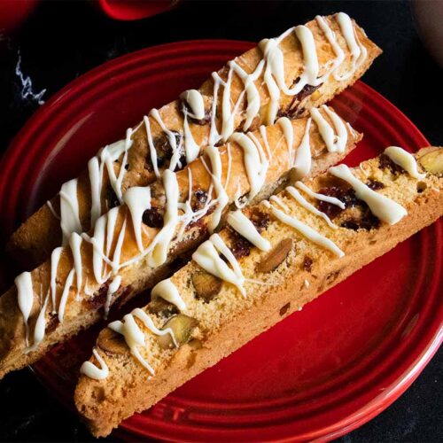 Slices of cranberry pistachio biscotti on a dark plate.