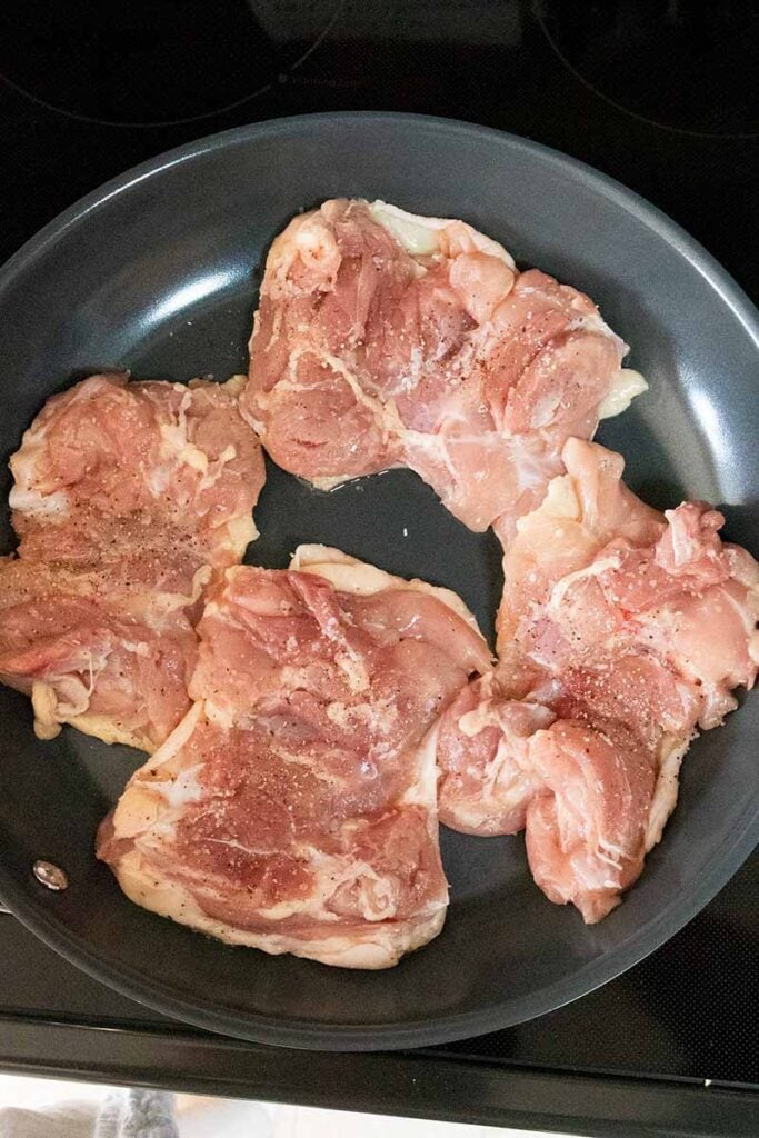 Raw chicken thighs in a skillet