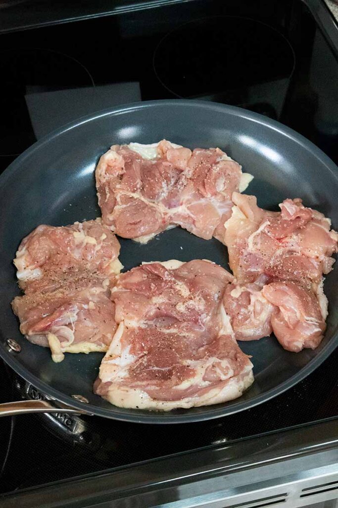 Raw chicken thighs in a skillet