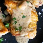 close up of a crispy boneless chicken thigh with a creamy garlic sauce