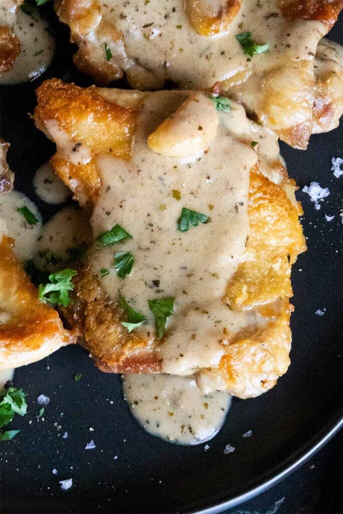 close up of a crispy boneless chicken thigh with a creamy garlic sauce