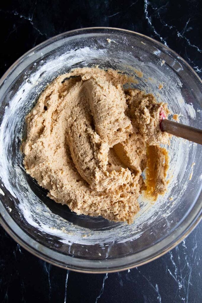 Peanut butter cookie dough in a glass mixing bowl.