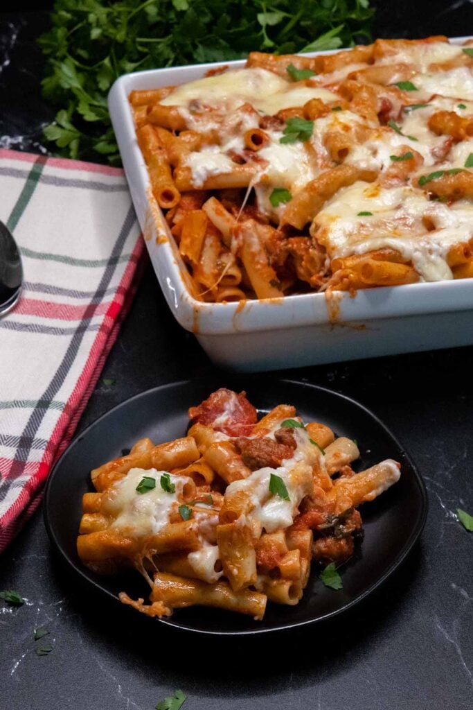 baked ziti with a serving on a black plate