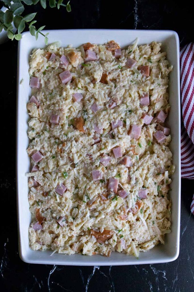 Uncooked strata in a white casserole dish.