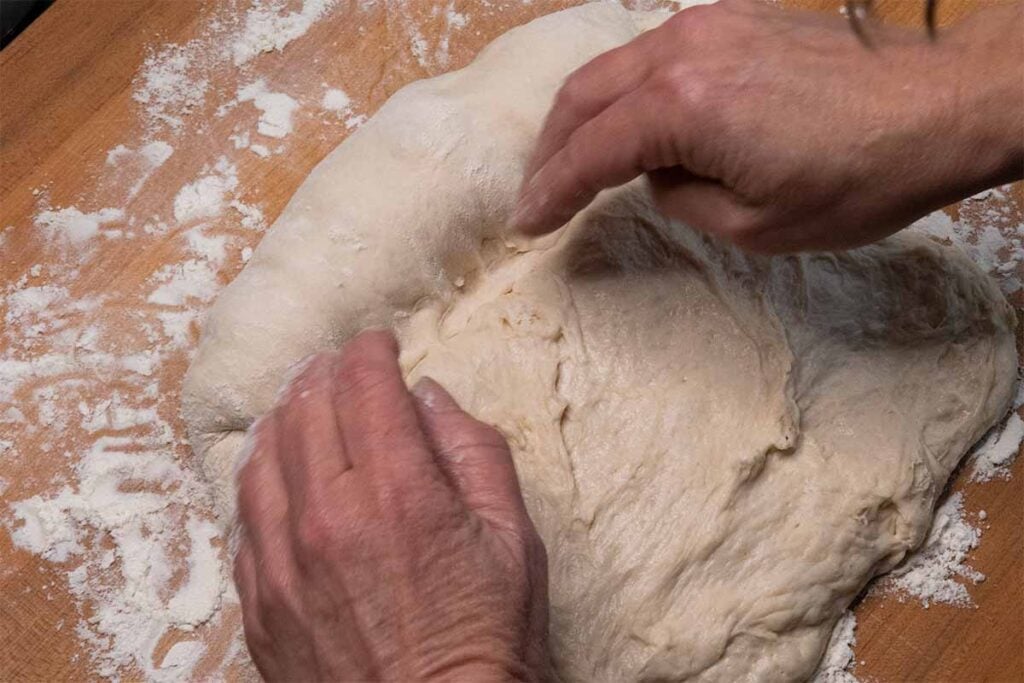 Rolling bread dough into a loaf.