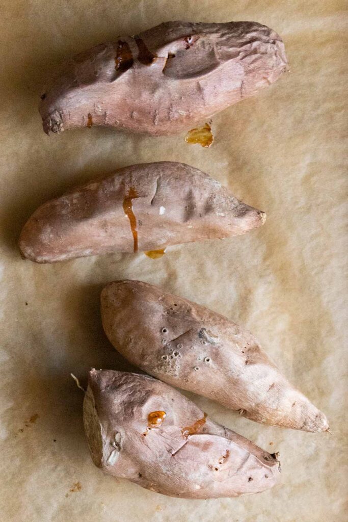 baked sweet potatoes on parchment lined baking sheet