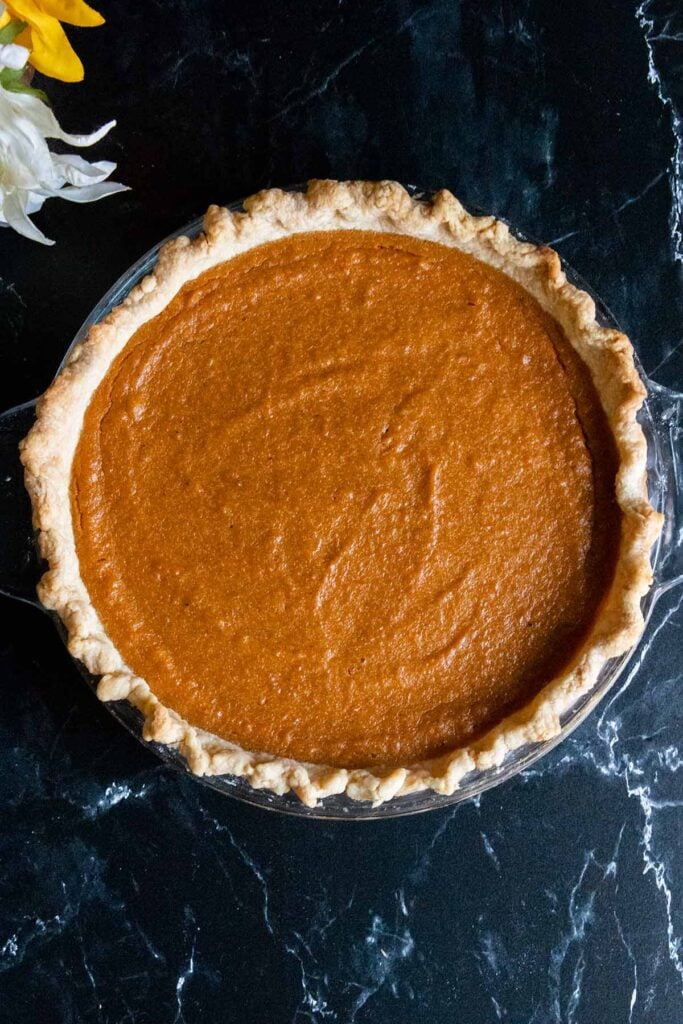 Whole southern sweet potato pie in a glass pie plate.
