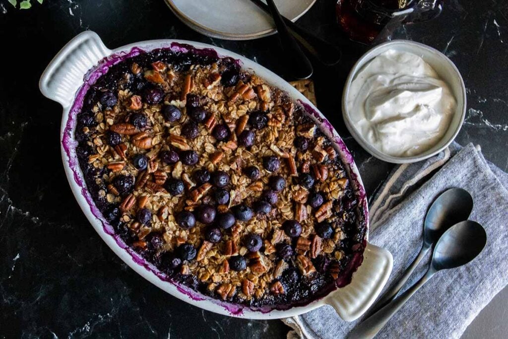 Blueberry baked oatmeal in a white oval baking dish.