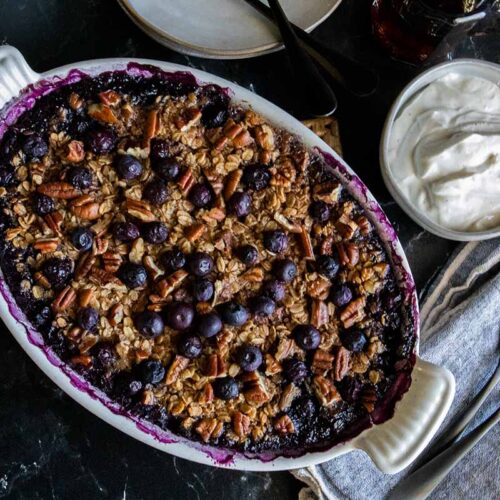 Blueberry baked oatmeal in a white oval baking dish.