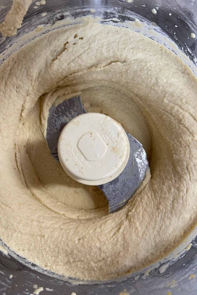 pureed hummus in the bowl of a food processor