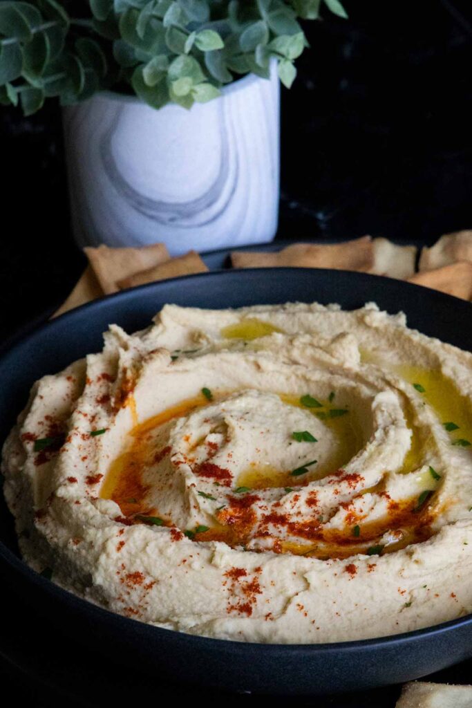 hummus in a black bowl surrounded by pita chips