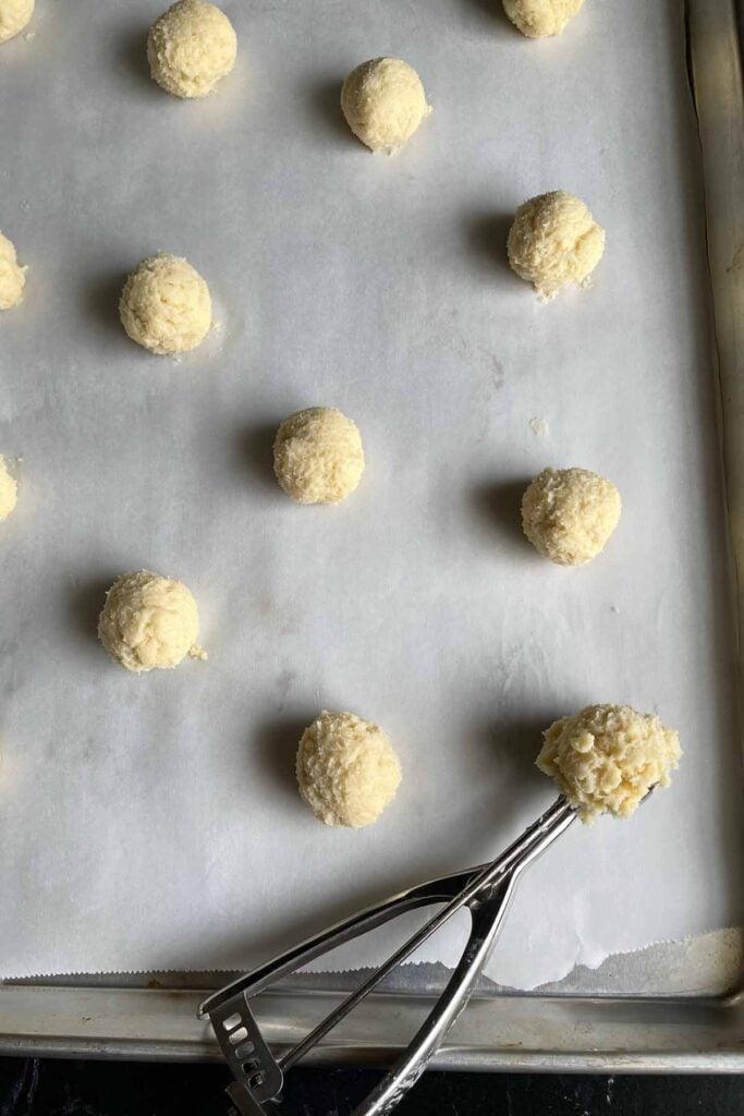 ricotta cookie dough balls on parchment lined baking sheet.